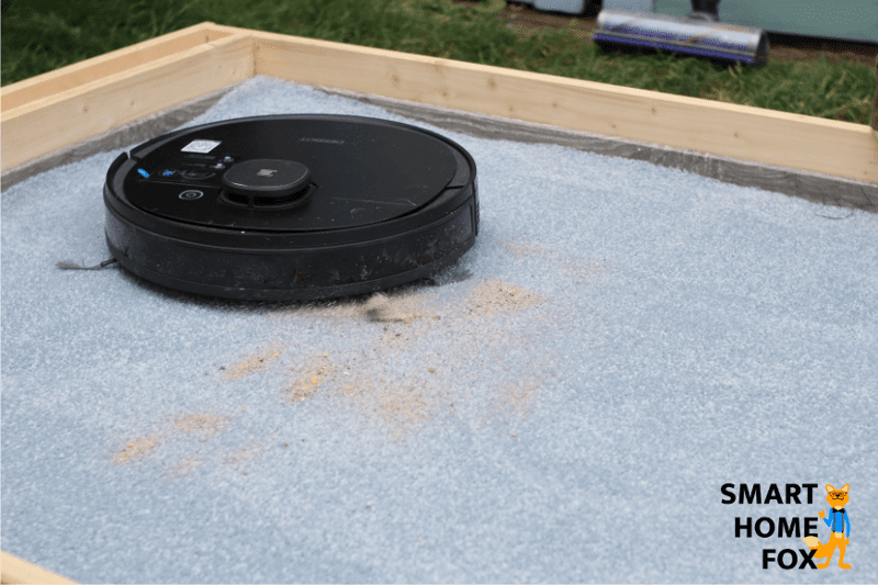 Deebot OZMO 950 во время испытания на всасывание песка на ковровом покрытии с высоким ворсом.